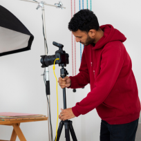 A man setting up a tripod and other gear for a video shoot represents the video production firm.