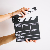 A person holding a clapper board against a white background from corporate video production company